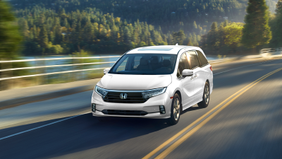 3/4 front view on white Odyssey driving on lakeside road.