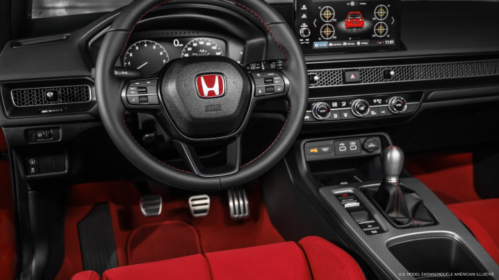 Medium interior closeup of steering wheel, dashboard, centre console, and gear shifter.
