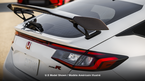 3/4 close up of white Type R’s rear wing spoiler. Red Type R in the background. 